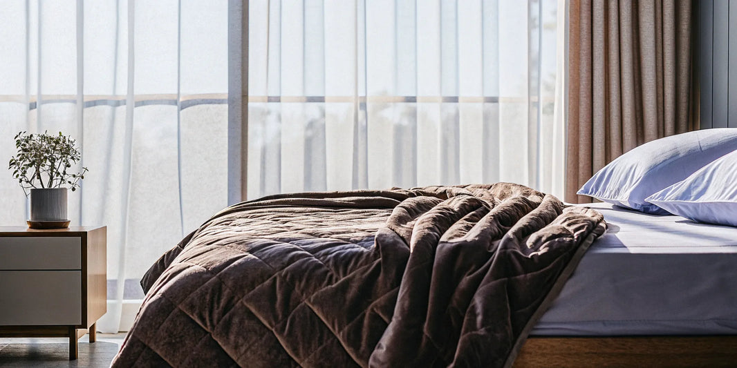 A king size cooling weighted blanket on a bed in a bright, comfortable bedroom.