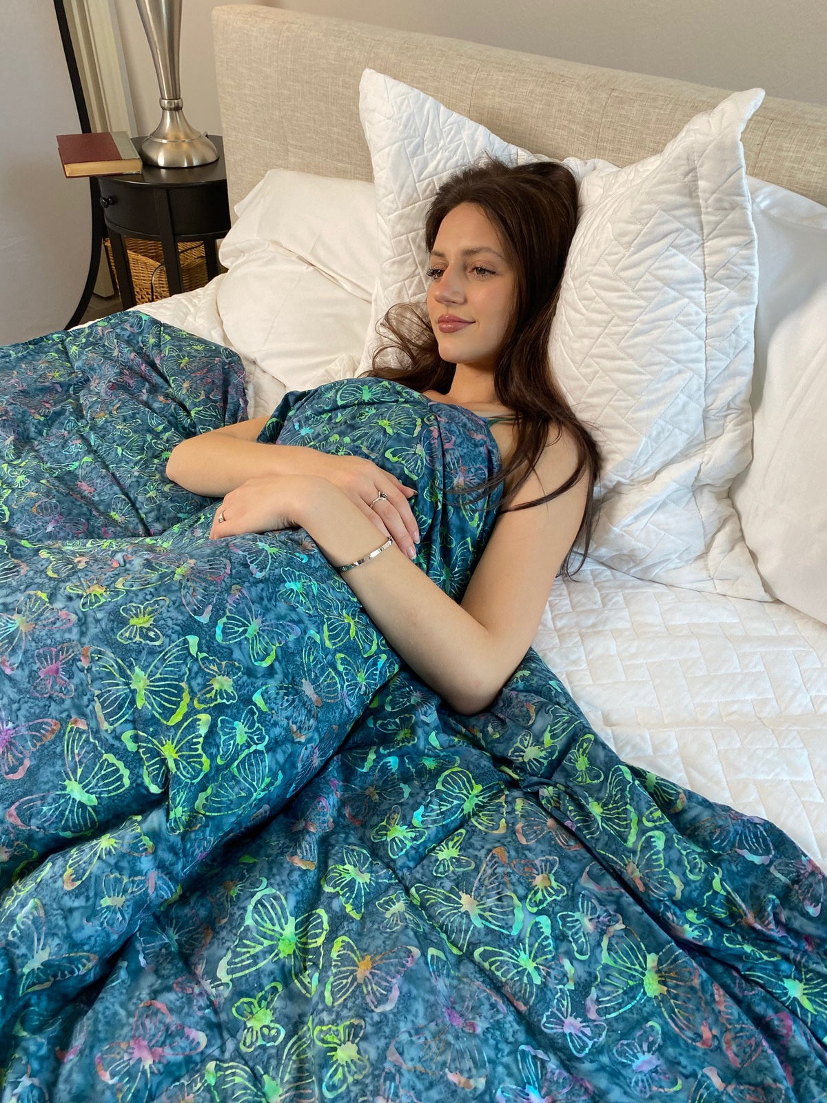 Woman snuggling under her Mosaic Weighted Blankets Teal Butterflies Weighted Blanket in bed