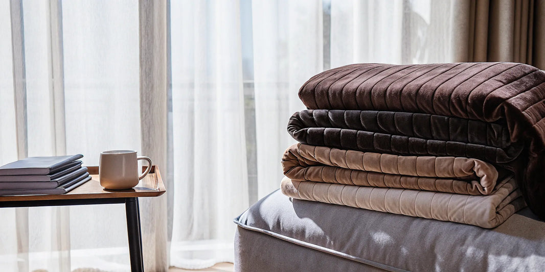 Best weighted throws for a couch stacked in neutral colors on a sofa.