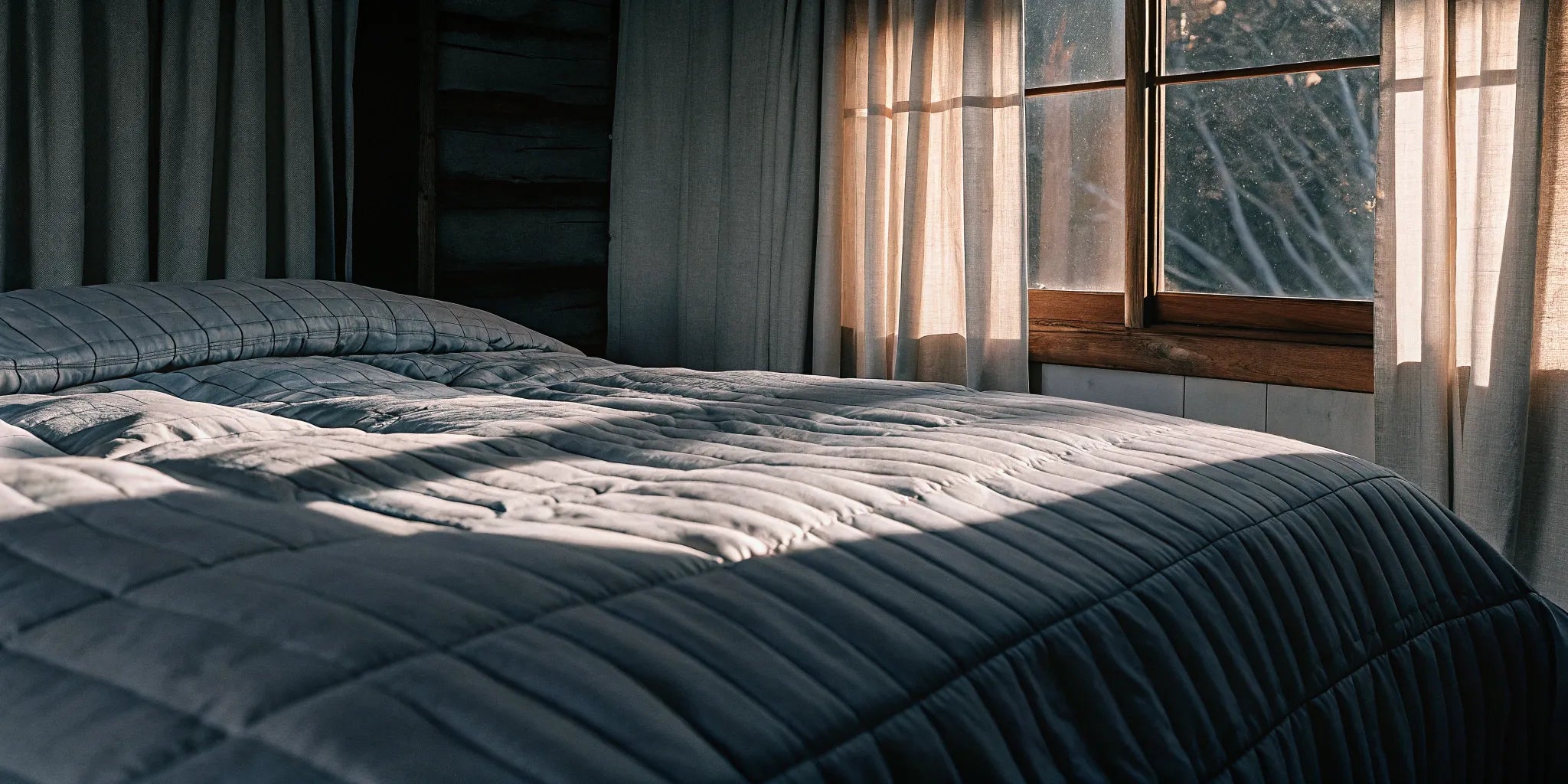 Lightweight cooling weighted blanket for summer on a bed in a sunlit room.