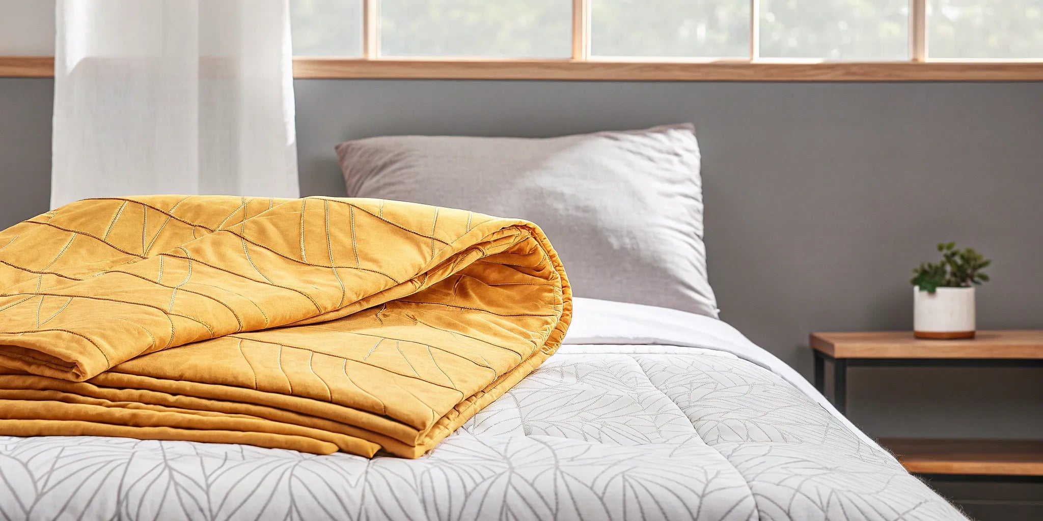 A personalized weighted blanket in mustard yellow on a bed for deep pressure comfort.