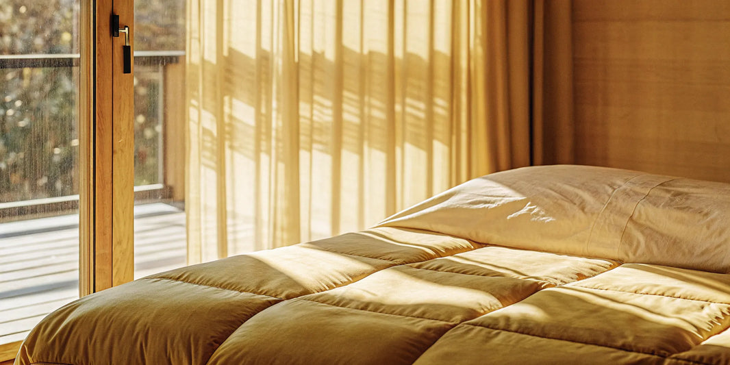 A calming blanket for anxiety attacks rests on a bed in a sunlit room.
