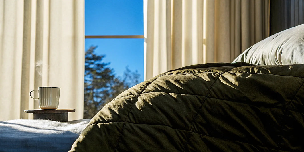 A soothing deep pressure blanket on a sunlit bed with a warm mug.