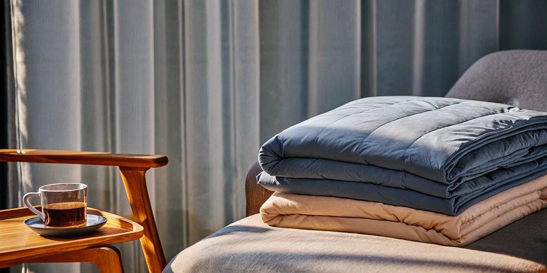 A stack of the best cotton weighted blankets folded neatly on a bed.