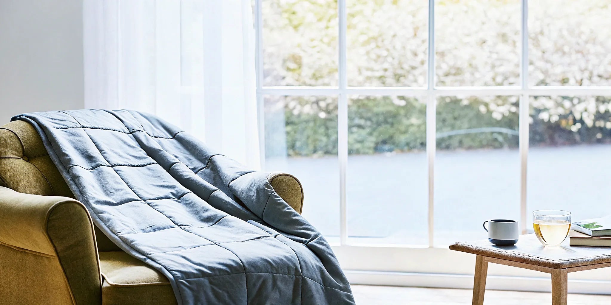 A cozy armchair with a weighted blanket for at-home deep touch pressure therapy for anxiety.