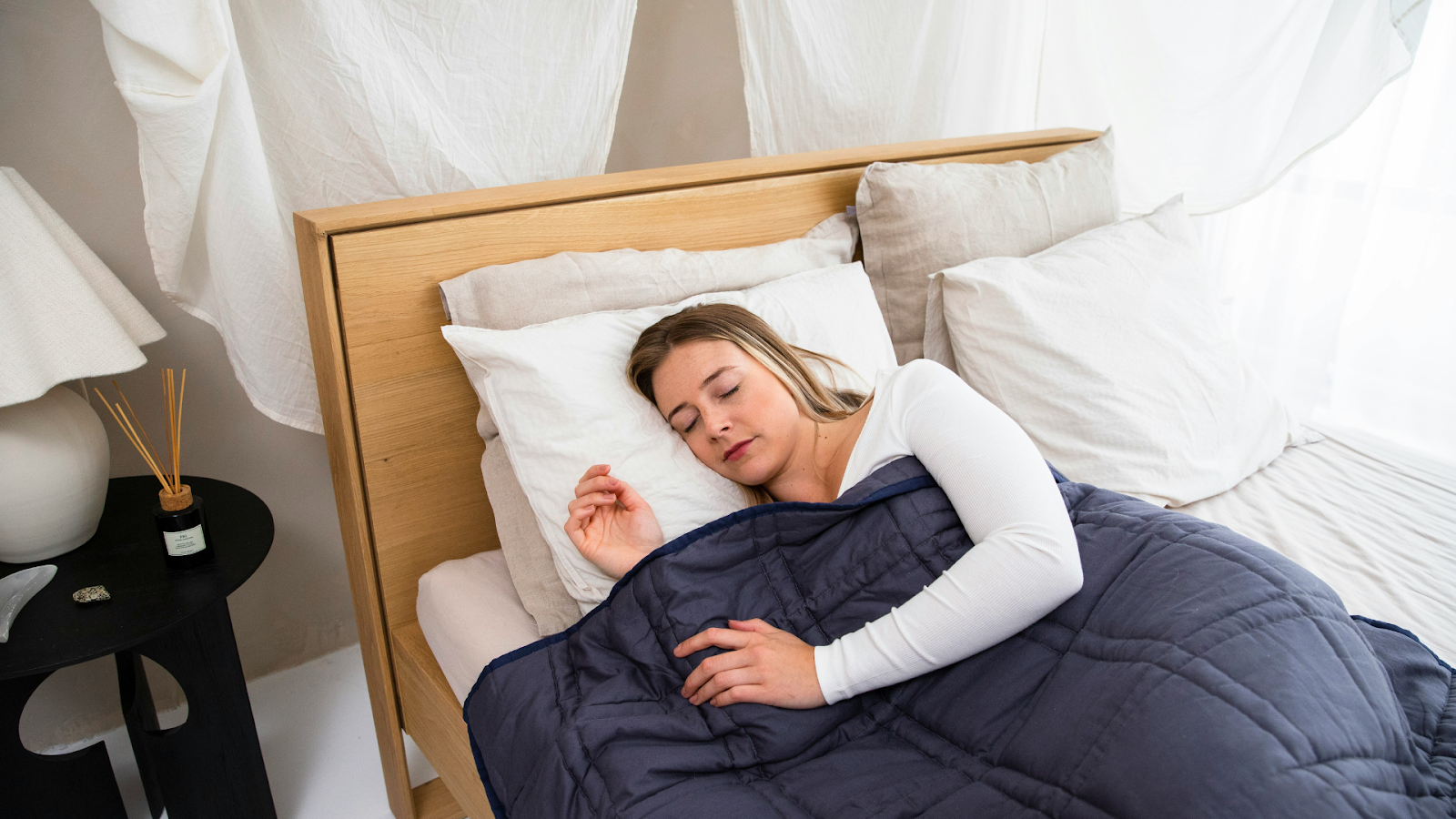 Woman sleeping under a weighted blanket in a bedroom setting