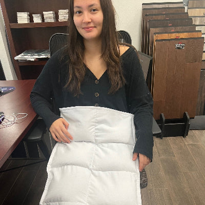 Person holding a white coolmax weighted lap pad in an office setting