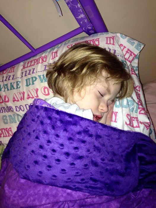 Little girl snuggled in her Mosaic Weighted Blankets Purple Minky Weighted Blanket in bed