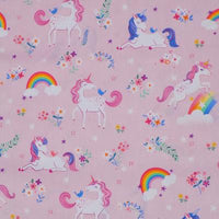 A kids' weighted blanket with a unicorn print design, over pink fabric rolled up and displayed on a white background.