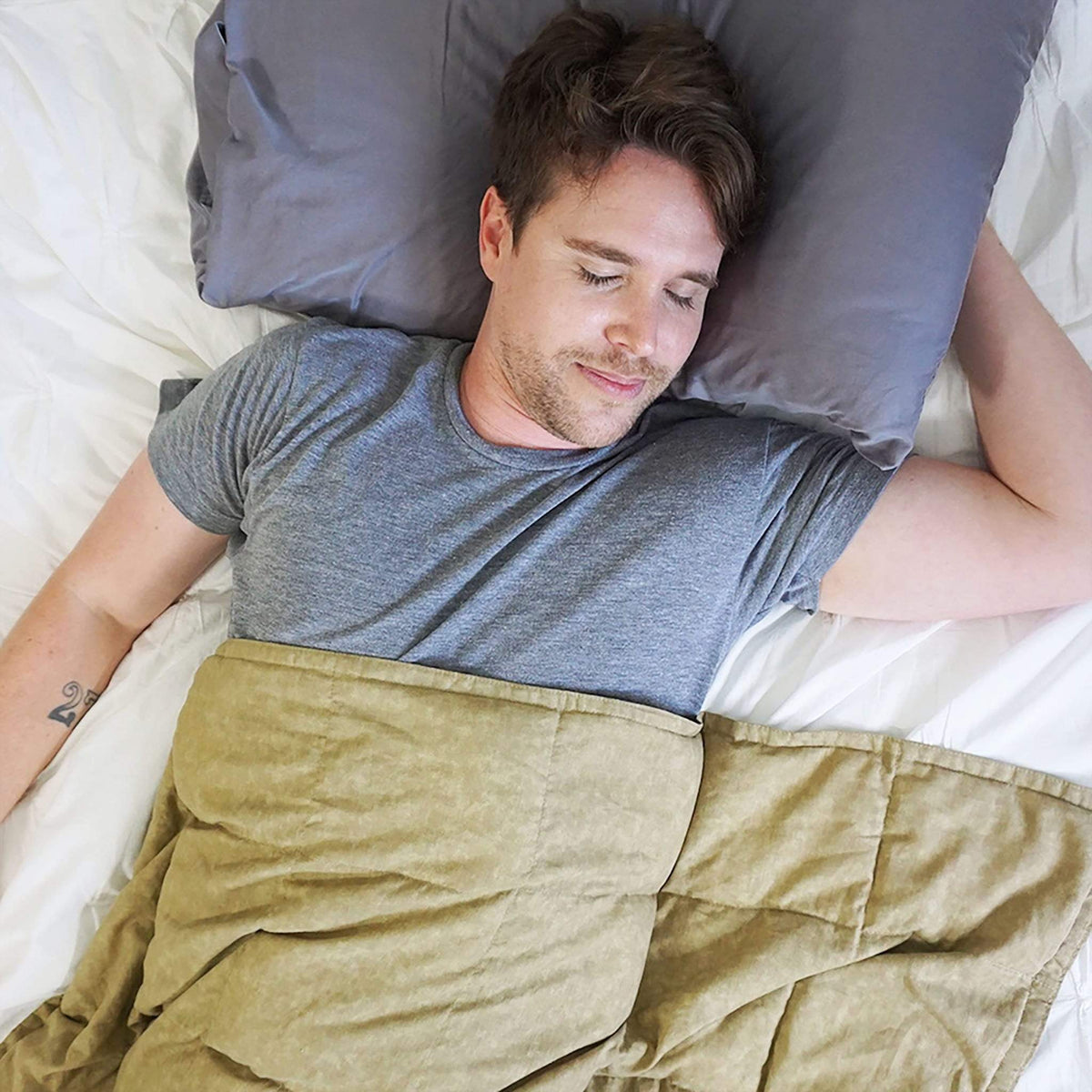Man sleeps in bed covered in a Mosaic Weighted Blankets Beige Weighted Blanket