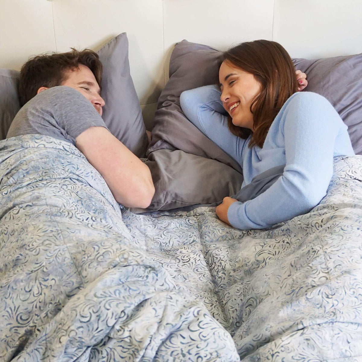 Couple snuggles under their Mosaic Weighted Blankets Dove Gray Batik Weighted Blanket in bed
