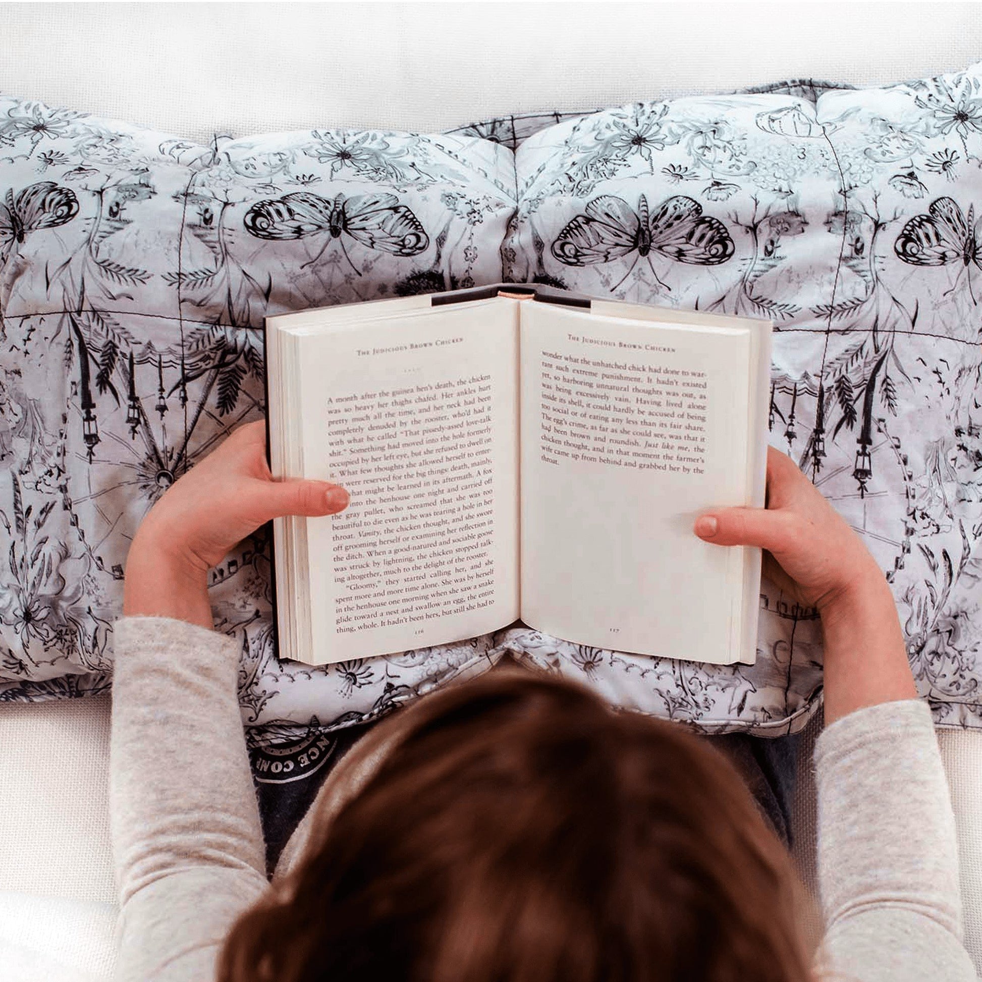 Girl reads while snuggled under her Mosaic Weighted Blankets Grab Bag Weighted Lap Pad