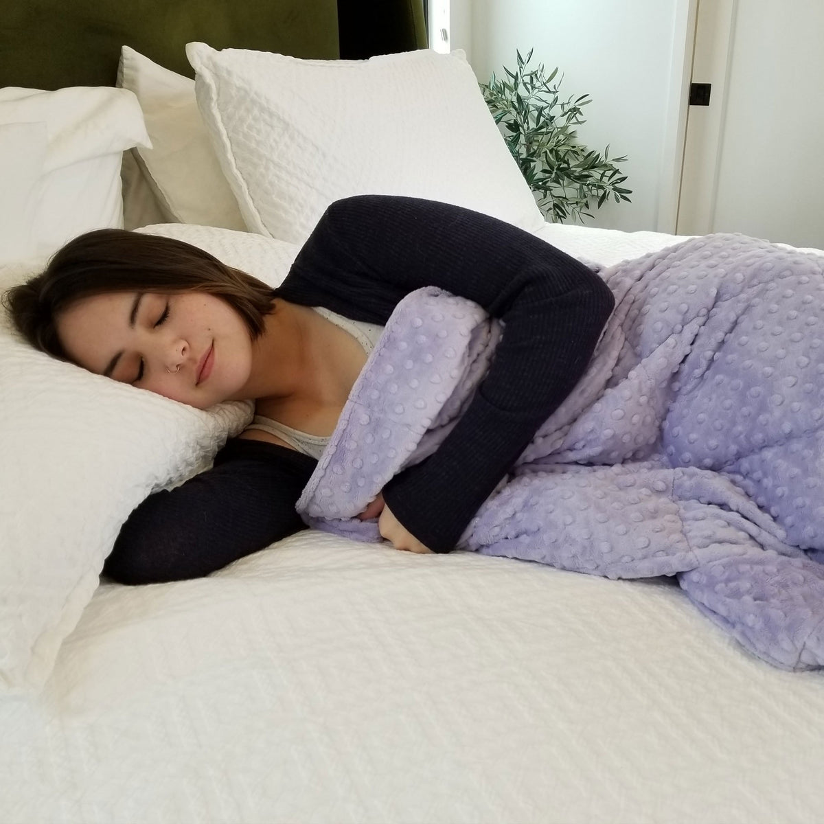 Woman in bed snuggled under her Mosaic Weighted Blankets Lavender Minky Weighted Blanket
