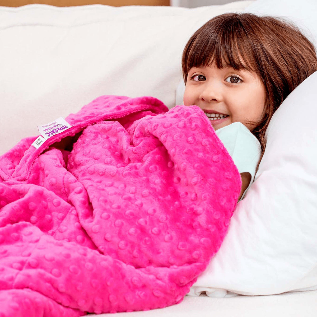 Little girl snuggled under her Mosaic Weighted Blankets Pink Minky Weighted Blanket on the couch