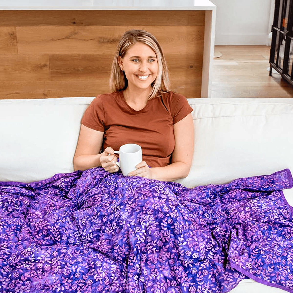 Woman in bed sipping from a mug under her Mosaic Weighted Blankets Purple in Bloom Weighted Blanket